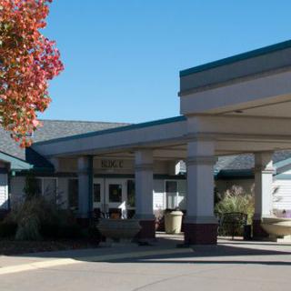 A building entrance surrounded by autumn foliage with a clear blue sky.