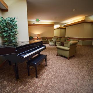 A cozy lounge area featuring a grand piano, comfortable seating, and soft lighting.