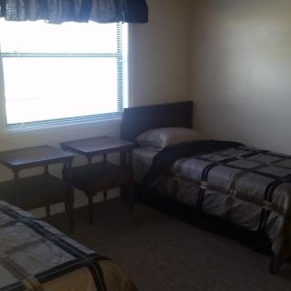 A simple bedroom with two single beds and a window.