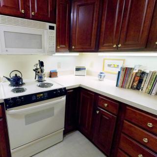 A cozy kitchen corner with dark wood cabinets, a stove, and a microwave, accompanied by a collection of cookbooks on the countertop.