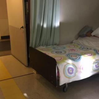 A hospital room with a single bed and privacy curtain.