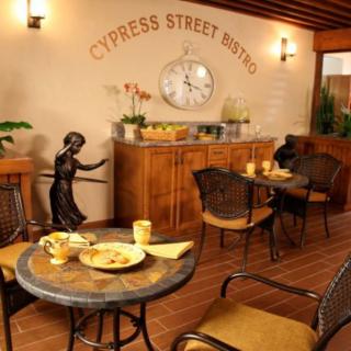A cozy indoor cafe setting with tables, chairs, and a wall clock, featuring decorative elements and warm lighting.