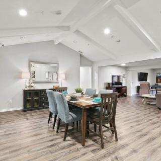A spacious and modern open-concept living area with a dining table, vaulted ceiling, and wood flooring.