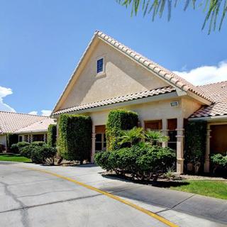 A sunny day view of a building with a driveway and well-maintained landscaping.