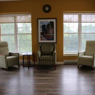 A cozy living room setup featuring two armchairs, a small table, and large windows allowing natural light to filter in.