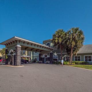 A building entrance with palm trees under a clear blue sky.