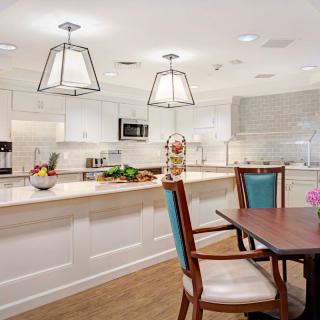 A modern kitchen with a spacious dining area featuring pendant lights and white cabinetry.