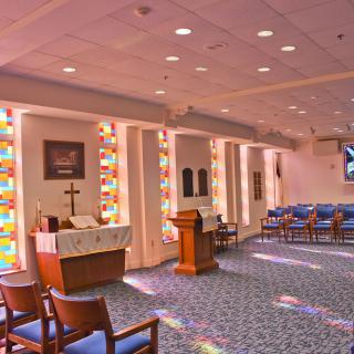 A serene chapel interior featuring stained glass windows and an altar.