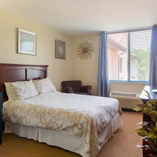 A cozy bedroom with a bed, chair, and window with curtains.