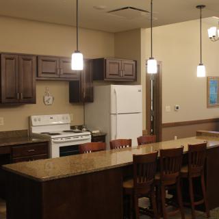A modern kitchen with dark wood cabinets, a large island countertop, and appliances.