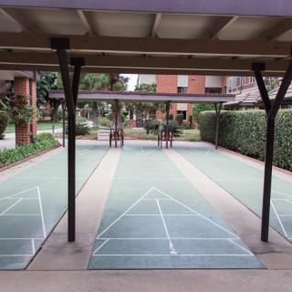 An outdoor covered shuffleboard court with two lanes marked by lines.