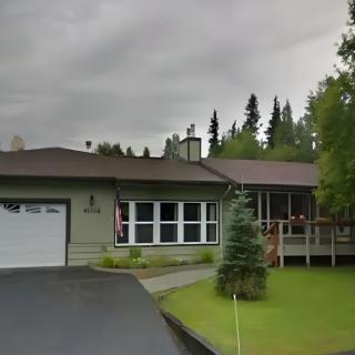 A suburban house with a driveway and well-maintained lawn on an overcast day.