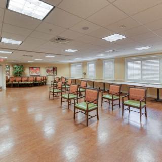 An empty meeting room with arranged chairs and wooden flooring.