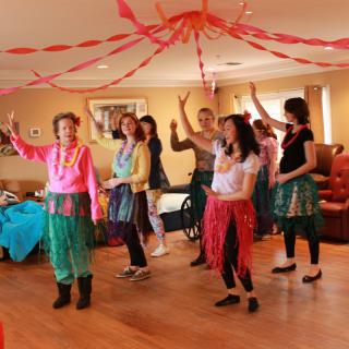 A group of people dancing indoors under colorful decorations.