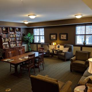 A cozy lounge area featuring comfortable seating, a bookshelf filled with books, and warm lighting.