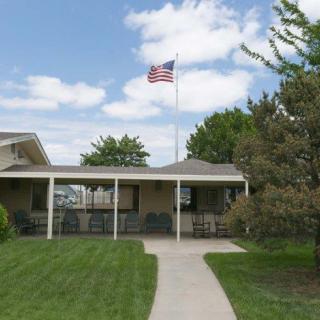 A building with an American flag flying on a flagpole, surrounded by a lawn and trees.