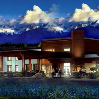A beautifully lit building set against a backdrop of mountains and dramatic clouds at dusk.