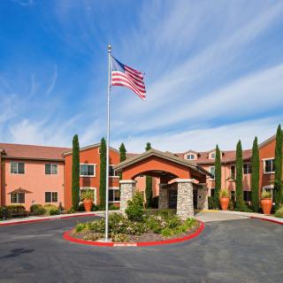 A hotel entrance with a flagpole displaying the American flag and well-maintained landscaping.