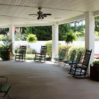 A peaceful covered porch with rocking chairs and lush greenery.