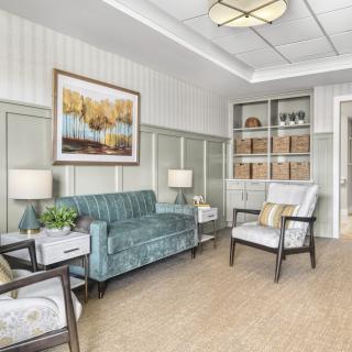 A modern living room with stylish furnishings, featuring a teal sofa, armchairs, and a bookshelf.