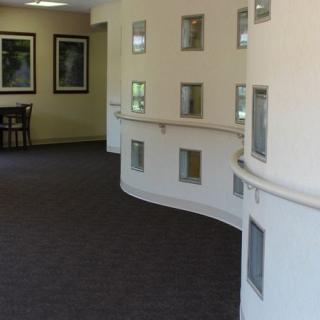 A modern interior hallway with a curved wall featuring small windows.
