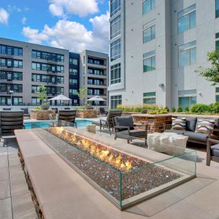 A modern apartment complex features a stylish outdoor seating area with a fire pit.
