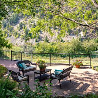 A tranquil patio setting with comfortable seating overlooking a lush, green landscape.