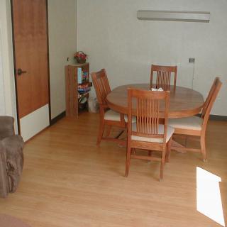 A cozy dining room with a round wooden table and chairs on a wooden floor.
