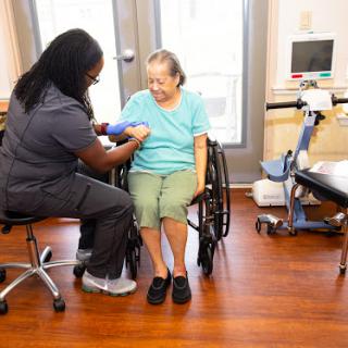 A healthcare worker taking the blood pressure of an elderly patient in a comfortable setting.