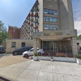 A city apartment building with parked cars in front.