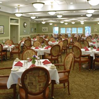 An elegant dining room with neatly arranged tables and chairs, set for a formal meal.