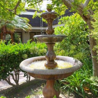 A decorative garden fountain surrounded by lush greenery.