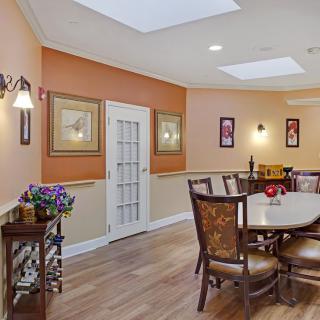 A warmly decorated dining room featuring a large table with chairs, adorned walls with artwork, and soft lighting.