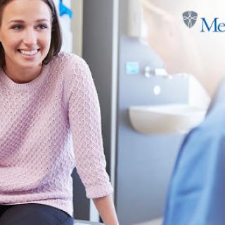 A smiling woman engages in a friendly medical consultation.