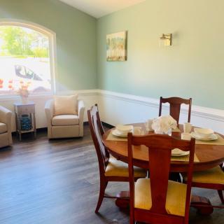 A cozy dining area with a round table set for four, featuring cushioned chairs and bright natural light filtering through a large window.