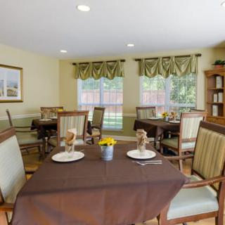 A cozy dining room with neatly arranged tables and chairs, featuring elegant window decor.