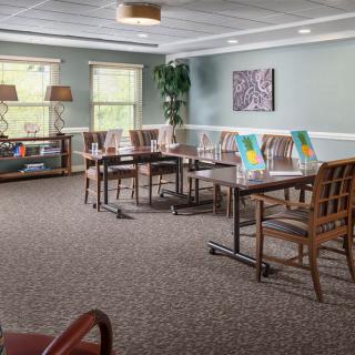A spacious dining area with neatly arranged tables and chairs, decorated with artwork and plants for a cozy atmosphere.