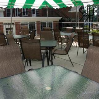 Outdoor patio area with tables and chairs under a striped awning.