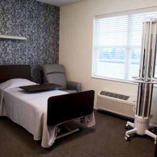 A neatly arranged patient room in a healthcare facility, featuring a hospital bed and comfortable seating.