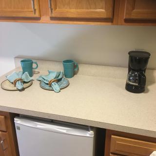 A kitchen countertop with two mugs, a stack of dish towels, and a coffee maker.