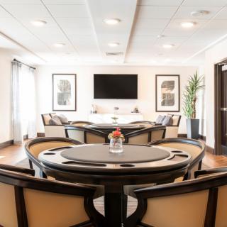 A modern game room featuring a poker table, ample seating, and a large television on the wall.