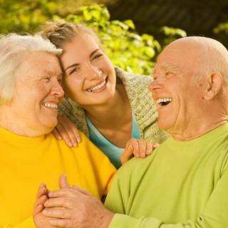 A happy family moment outdoors with two elderly individuals and a younger person smiling together.