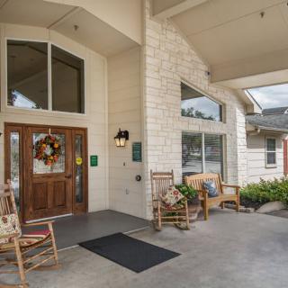 A welcoming building entrance with rocking chairs and a decorative wreath on the door.