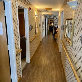A view of a well-lit hallway with wooden flooring and multiple doors.