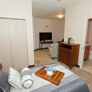 A cozy bedroom with a view into a living area featuring a television and comfortable seating.