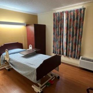 A hospital room with a single bed, wardrobe, and colorful curtains.