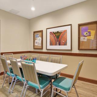 A small conference room with a white table and blue chairs, adorned with framed artwork on the walls.