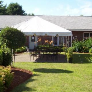 A beautifully landscaped garden with a seating area under a white tent.