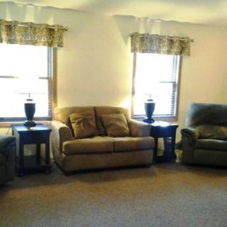 A cozy living room with sofas, armchairs, and lamps placed by the windows.