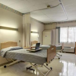 A hospital room with two beds and a laptop on one of them.